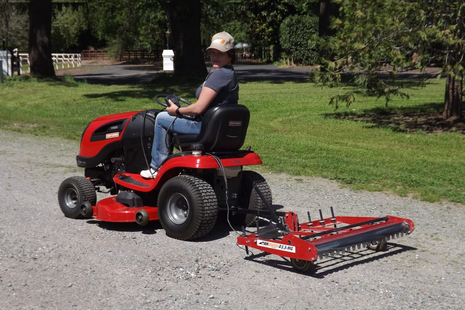 A woman riding a lawn mower with a leveling drag